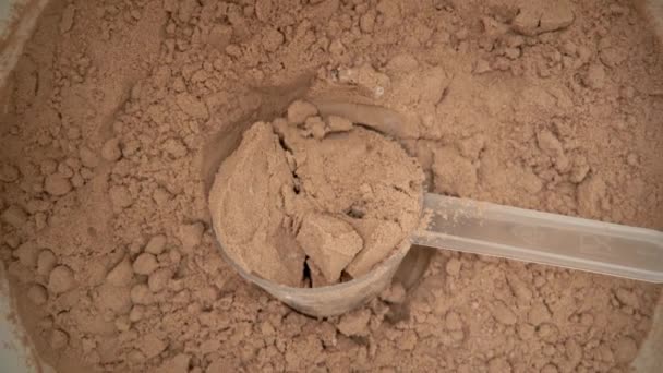 Sparare a una macro estrema, allontanandosi da un misurino con polvere di proteine del cioccolato, in un serbatoio. Vista dall'alto. — Video Stock