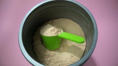 Bir tankın içinde, vanilyalı vegan protein tozuyla ölçüm kabından uzaklaşmak. Üst görünüm.