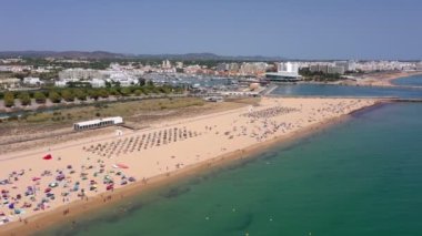 Hava videosu, güzel Portekiz plajları, turist kasabası yakınlarındaki, Vilamoura, Falesia, rıhtım manzaralı. Turistler güneşleniyor..