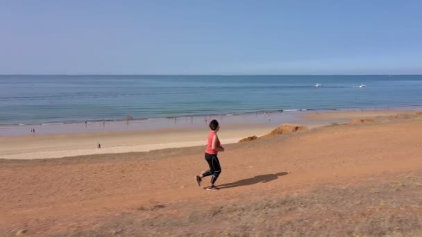 Een vrouw van middelbare leeftijd, overgewicht, traint cardio joggen, op het strand, voor gewichtsverlies. Zeegezicht op de achtergrond. — Stockvideo