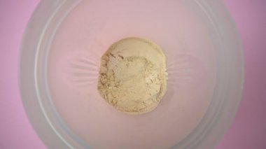 Ekstrem makro video, bir sporcu kas kütlesi kazanmak için protein ve spor besinleriyle karıştırıcıya su döker. Üst Manzara. Yavaş çekim.