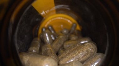 Doğal bitkisel ilaç kapsülleri haplar, bir kavanozun içinde. Aşırı makro hareket halinde.