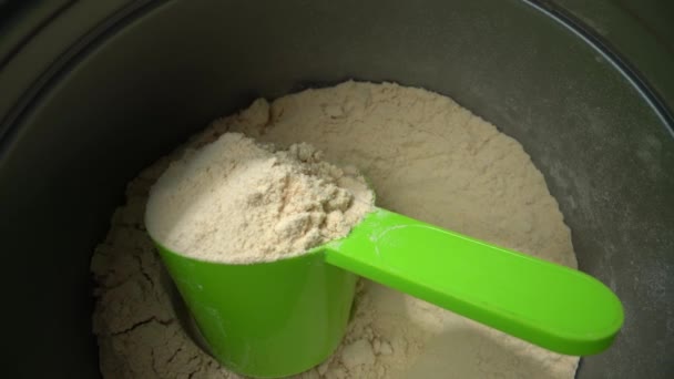 Sparare a una macro estrema, allontanandosi da un misurino con polvere proteica vegana alla vaniglia, in un serbatoio. Vista dall'alto. — Video Stock