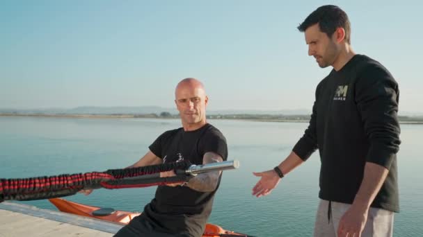 Un windsurfeur sur une boule de stabilisation stimule la conduite sur une planche avec des extenseurs en caoutchouc. Développer l'équilibre et la stabilité. Portugal Faro 2021 15 mars — Video