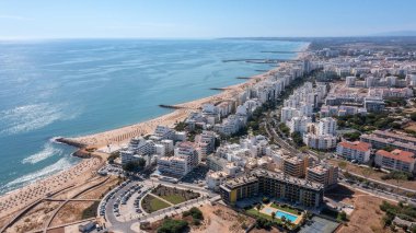 Portekiz 'in Quarteira şehrinin güzel şehir manzaraları. Kumsal mevsiminde, güneş banyosu yapan turistlerle sahilde..
