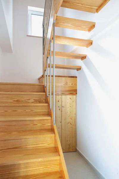 Moderne Holztreppe mit Handlauf und Stauraum, vom ersten Stock bis zum zweiten Stock. Vertikales Bild. — Stockfoto