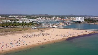 Hava videosu, güzel Portekiz plajları, turist kasabası yakınlarındaki, Vilamoura, Falesia, rıhtım manzaralı. Turistler güneşleniyor..