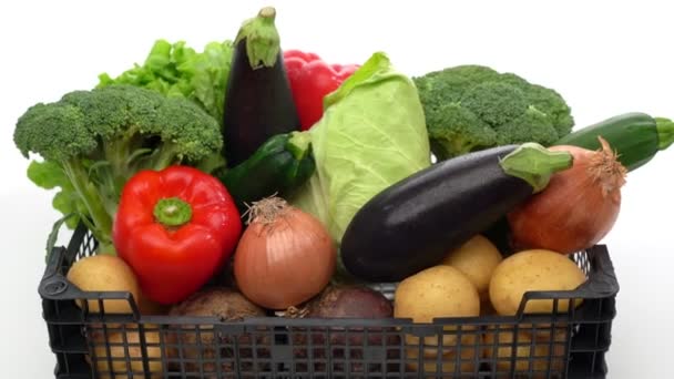 Delivery box with assorted fresh organic vegetables, ready for sale or charity. In motion backward movement on a white background, close-up. — Stock Video