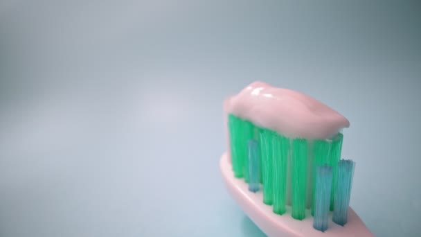 Filmagem de vídeo macro extrema, escova de dentes em um fundo azul em movimento, pasta de dentes na escova. Movimento para a frente, close-up. — Vídeo de Stock