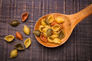 İtalyan makarna kabukları bir tahta kaşık içinde. Doku.