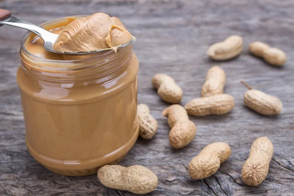 Jar of peanut butter with nuts. On wooden texture. – stockfoto