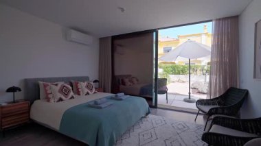 Rahat, modern bir otel odasında şemsiyeli ve sandalyeli bir veranda, doğal ışık manzarayı aydınlatıyor, rahatlatıcı bir atmosfer yaratıyor.