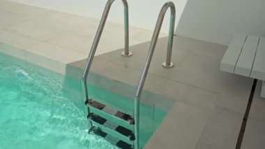 Kristal berrak turkuaz su kademeli olarak çağdaş bir yüzme havuzunu doldurur, izleyicileri güneşli bir günde serin derinliklerine serinletici bir dalış hayal etmeye davet eder.