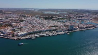 Ayamonte Havacılık Koyu 'na yaklaşan yolcu feribotuyla birlikte kumlu buruna, sahil kenarı arka planına ve uzak bataklıklara doğru sakin turkuaz suyu geçerek hava görüntüsü..