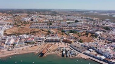 Ayamonte Havacılık manzaralı balıkçı köyü ve kumlu kumsalın hava görüntüsü, küçük kayıklar, balıkçı aktiviteleri, sığ turkuaz su ve sıkıştırılmış beyaz kıyı evleri..