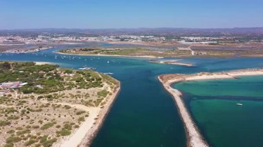 Tavira Portekiz 'in insansız hava aracı görüntüsü. Tavira kıyı şeridi yakınlarında kumlu tükürükler, sakin zümrüt suyu, küçük boş zaman tekneleri, plaj bantları ve korunmuş koruma altındaki turkuaz girişi.