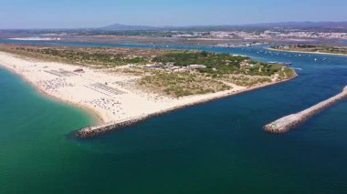 Tavira Portekiz 'in insansız hava aracı görüntüsü kıyı tükürüğü ve kanallarının dramatik havasını Ria formozasına, körfezde gezinen botları ve güneşli sahil mühendisi ziyaretçilerini gösteriyor.