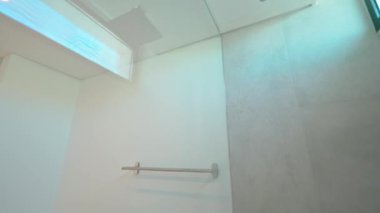 Minimalist beyaz fayanslı banyoda profesyonel duş başlığı kurulumunu kaydeden sıralı video boş alanı bitmiş kuruluma dönüştürüyor.