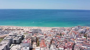 Güneşli sahil manzarası, canlı sahil manzarası hareketli, canlı şemsiyeli ve tekneli kıyı şeridi renkli şemsiyeli ve hareketli kalabalıklı canlı sahil resmi.