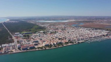 Ria Guadiana yakınlarındaki Tavira Portekiz 'in hava manzaralı kıyı yolu ve şehir sınırının drone görüntüleri orman kumullarını, sahil şeritlerini ve marina hattını gösteriyor.