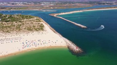 Tavira Portekiz 'in hava manzaralı drone görüntüsü. Tekne kumlu bölgeye yakın bir yerde dalgalanma yapıyor. Güneş dolu sahil kaptanı ve gündüz gezginleri kıyı yolculuğunun keyfini çıkarıyorlar.