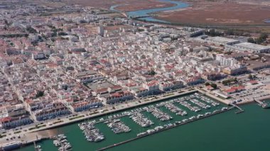 Portekiz Algarve limanının insansız hava aracı görüntüsü Vila Real Santo Antonio 'daki gezinti güvertesi boyunca botlarla dolu, turkuaz sularda yatlar ve balıkçı tekneleri, ideal