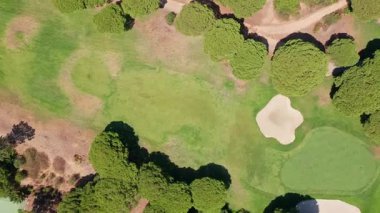 Golf sahasının tepeden tırnağa görüntüsü yeşil kumdan sığınak, çim alanı ve ağaçların kesilmiş çimenlere gölge düşürdüğünü gösteriyor. Açık hava eğlencesi ve spor manzarası tasarımı kavramı