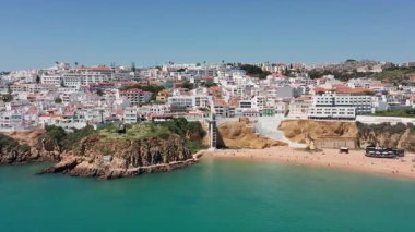 Praia dos Pescadores plajı, dramatik uçurumlar, turkuaz su ve kenti kıyı şeridine bağlayan dikey sahil asansörü ile Albufeira 'nın sahil drone görüntüsü. Kentsel sahil erişimi kavramı 