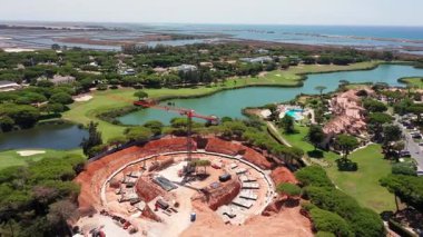 Portekiz, Vale do Lobo 'daki yuvarlak inşaat alanının havadan görünüşü. Etrafı golf sahası, villa, lagün ve okyanusla çevrili. Lüks kıyı gelişimi ve gayrımenkul altyapısı kavramı