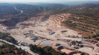 Maden çıkarma panoraması, depolama alanları, yükleme bölgeleri, işleme düğümleri ve erişim yolları, çevresindeki çalılıklar ve uzak çıkıntılar ile endüstriyel ahenk