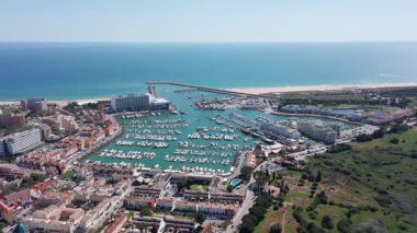 Vilamoura hava manzaralı geniş kıyı manzaralı vilamoura geniş marina havzası, uzun kumlu plajlar, koruyucu dalgalar ve yeşil parklar, sakin deniz ve panoramik ufku gösteriyor.