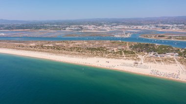 Tavira Portekiz Algarve. Altın kum ve turkuaz suyun yer aldığı, doğal güzelliği ve huzurlu sahil çevresini ön plana çıkaran sakin kumsal perspektifi.