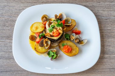 Taze balık filetosu, kızarmış patates ve beyaz tabakta taze sebzelerle güzel düzenlenmiş bir deniz ürünleri tabağı, aşçılık sanatını ve lezzeti gözler önüne seriyor.