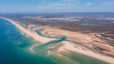İnsansız hava aracı görüntüsü Ria Formosa ve Praia de Faro 'yu gösteriyor. Görüntü kıyı şeridini kum ve suyun alçak gelgitte birleşmesiyle yakalıyor..