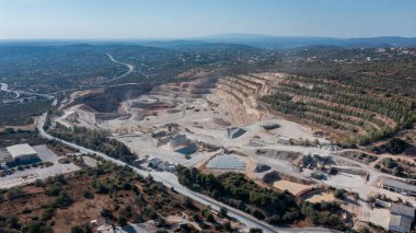 Açık madencilik alanında geniş bir sanayi ortamında kömür ve çimento çıkarımı vurgulanan ağır makineler ve toprak katmanları yer almaktadır.