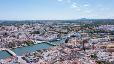 Algarve 'deki Tavira, binalarını, Gilao Nehri' ni ve bulutlu açık bir gökyüzünün altındaki yeşil alanları gösteriyor..