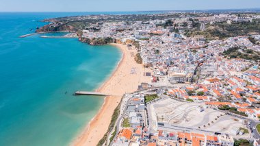 Turistler, Portekiz 'in Albufeira kentindeki Praia dos Pescadores plajında güneşli bir günün keyfini çıkarırken, marina ve kıyı boyunca renkli binalar görülebiliyor..