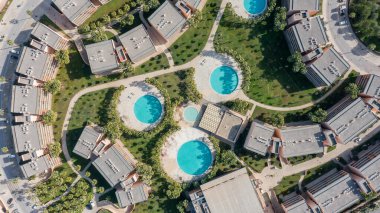 Aerial view of a residential area in Albufeira, Algarve, Portugal. The scene includes several swimming pools surrounded by green spaces and buildings.