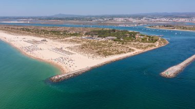 Tavira Portekiz Algarve. Manzaralı sahil manzarasında altın kumlar ve turkuvaz suları, dinginlik için sakin bir atmosfere sahip canlı bir kıyı manzarasını vurguluyor.