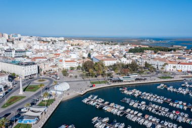 Turistler Faro 'daki Ria Formosa ve eski kenti ziyaret ederken tekneler yanaştı. Sahne, Portekiz 'deki Algarve bölgesinin hareketli faaliyetlerini gösteriyor..