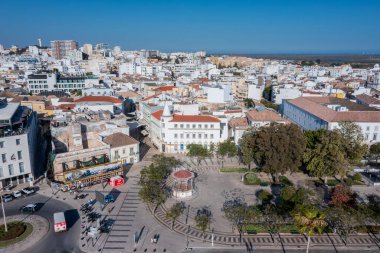 Görüntü Faro 'nun eski kasaba bölgesini gösteriyor. Binalar, sokaklar ve yakındaki rıhtımlar. Ziyaretçiler Ria Formosa 'yı ve şehrin yoğun atmosferini görebiliyorlar..