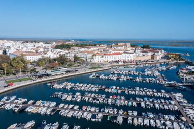 Faro Algarve 'de birçok tekneyle dolu bir rıhtım gösteriyor. Eski kasaba arka planda duruyor, tipik mimari ve açık mavi gökyüzünü sergiliyor..