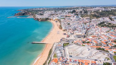 Ziyaretçiler, Portekiz 'in Albufeira kentindeki marina yakınlarındaki plajda güneş canlı kasaba ve sahil şeridinde parlarken bir araya geldiler..