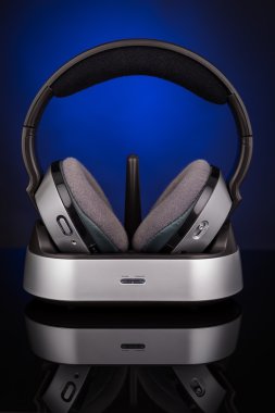 Mavi bir arka plan üzerinde kablosuz kulaklık. Yansıması ile.