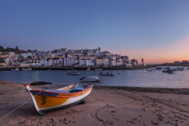 Akşam balıkçılar, Ferragudo Köyü yukarıda. Ön planda geleneksel tekne.