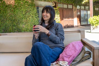 Kanepede geleneksel eşinin keyfini çıkarırken gülümseyen bir kadın..