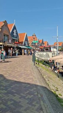 Volendam Hollanda 'daki geleneksel evlerle tarihi liman boyunca gezinen turistler