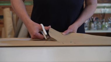 Moda tasarımcısının elleri makasla kahverengi kağıt desenini keserken.