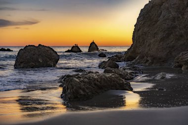 Malibu, California 'daki El Matador Eyalet Sahili' ndeki kayalık gel-git havuzlarının üzerinde altın gün batımı