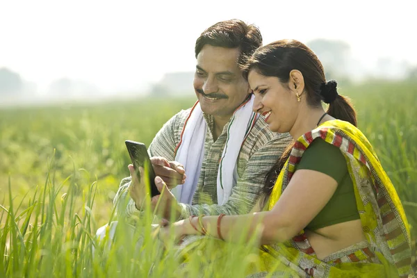 Tarımsal alanda cep telefonu kullanan kırsal bir çift.